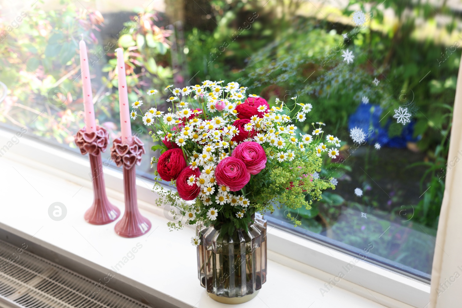 Photo of Beautiful ranunculus flowers and chamomiles in vase on windowsill indoors