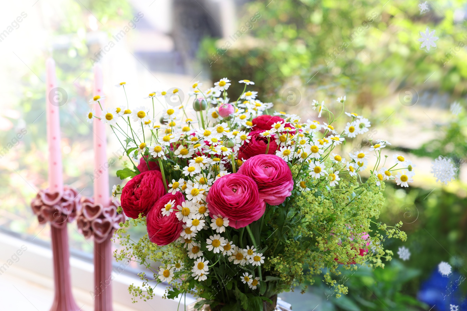 Photo of Beautiful ranunculus flowers and chamomiles near window indoors