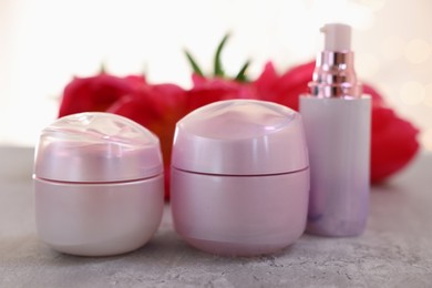 Set of different cosmetic products and peony flowers on gray table, closeup