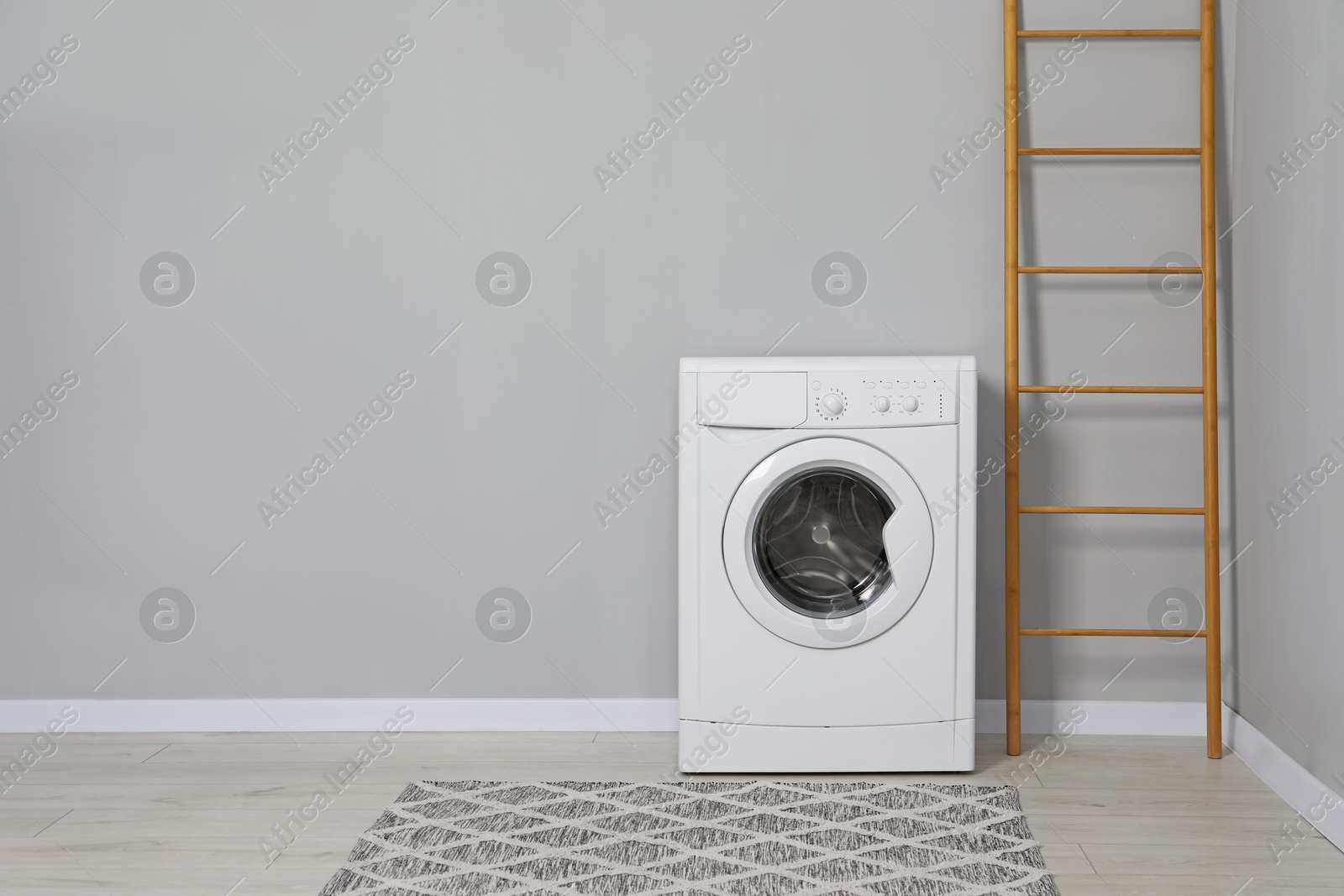 Photo of Washing machine and ladder near grey wall indoors, space for text