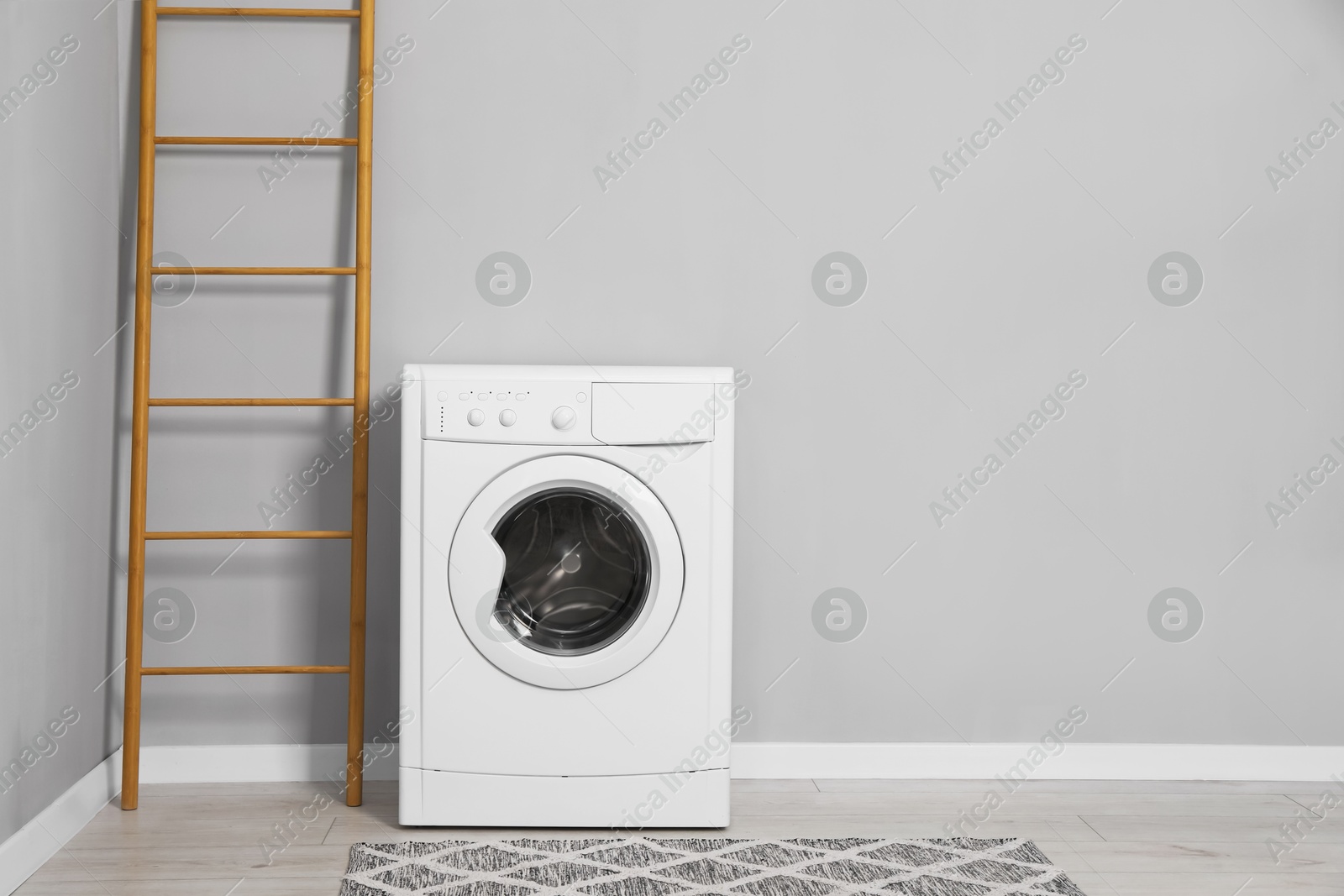 Photo of Washing machine and ladder near grey wall indoors, space for text