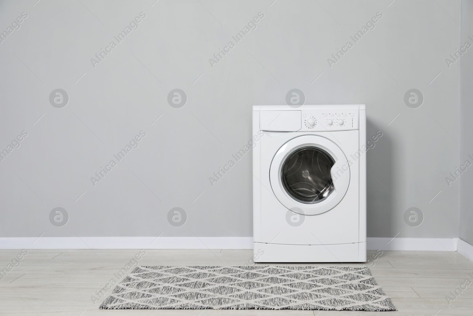 Photo of Washing machine near grey wall indoors, space for text