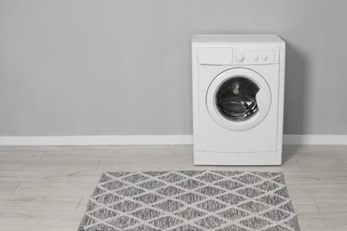 Photo of Washing machine near grey wall indoors, space for text