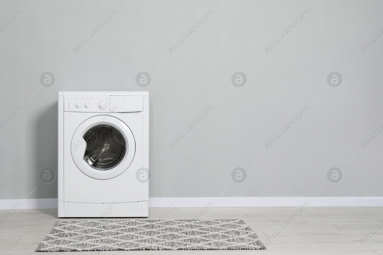 Photo of Washing machine near grey wall indoors, space for text