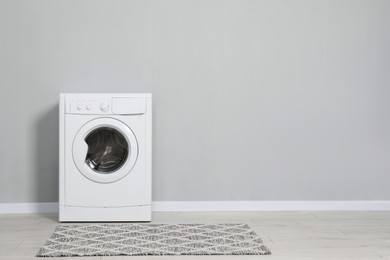 Washing machine near grey wall indoors, space for text