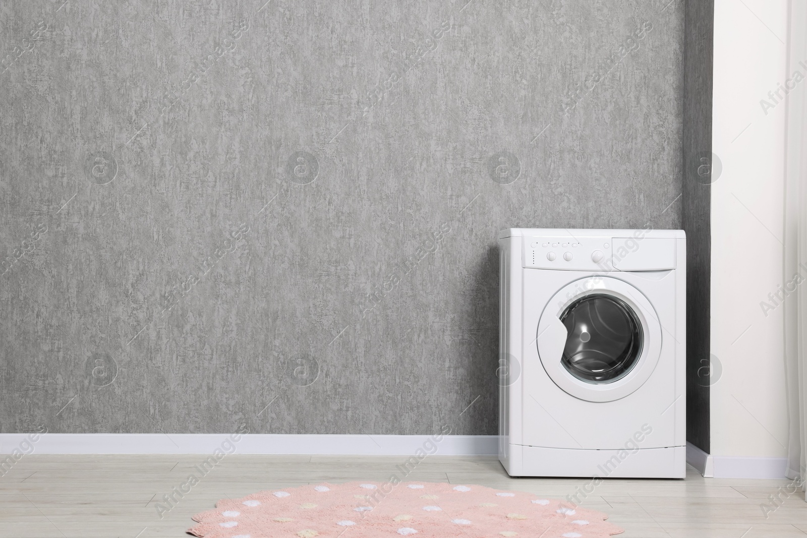 Photo of Washing machine near grey wall indoors, space for text