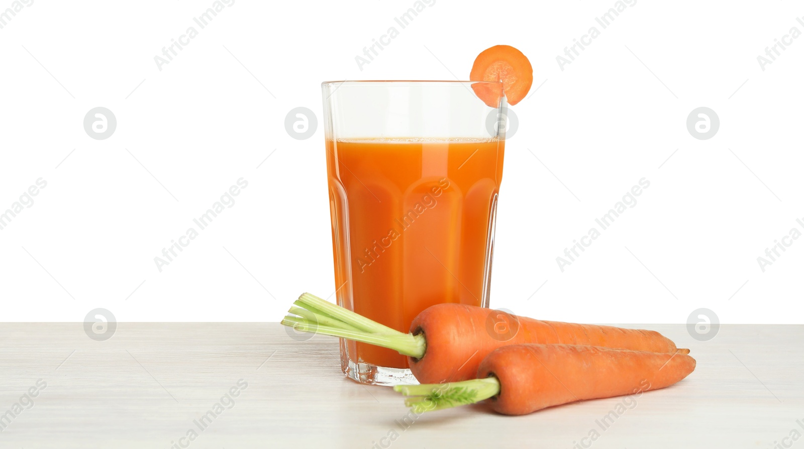 Photo of Fresh carrot juice in glass and vegetables on wooden table against white background