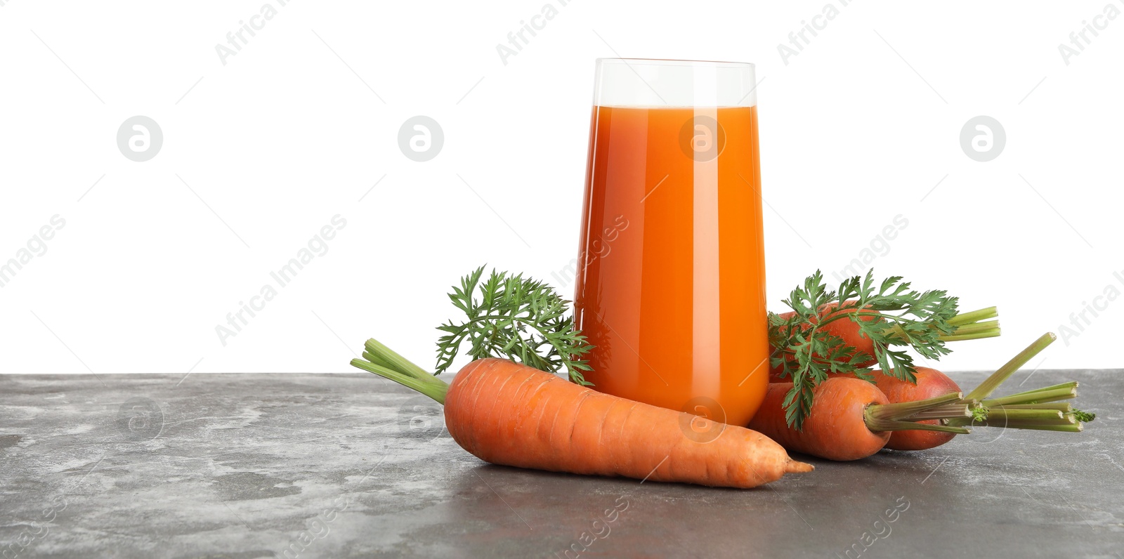 Photo of Fresh carrot juice in glass and vegetables on grey textured table against white background. Space for text