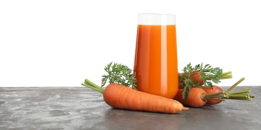 Photo of Fresh carrot juice in glass and vegetables on grey textured table against white background. Space for text