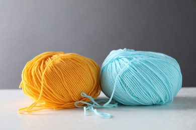 Two soft skeins of yarn on white table against grey background