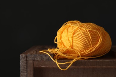 Photo of Skein of orange yarn on wooden stand, space for text