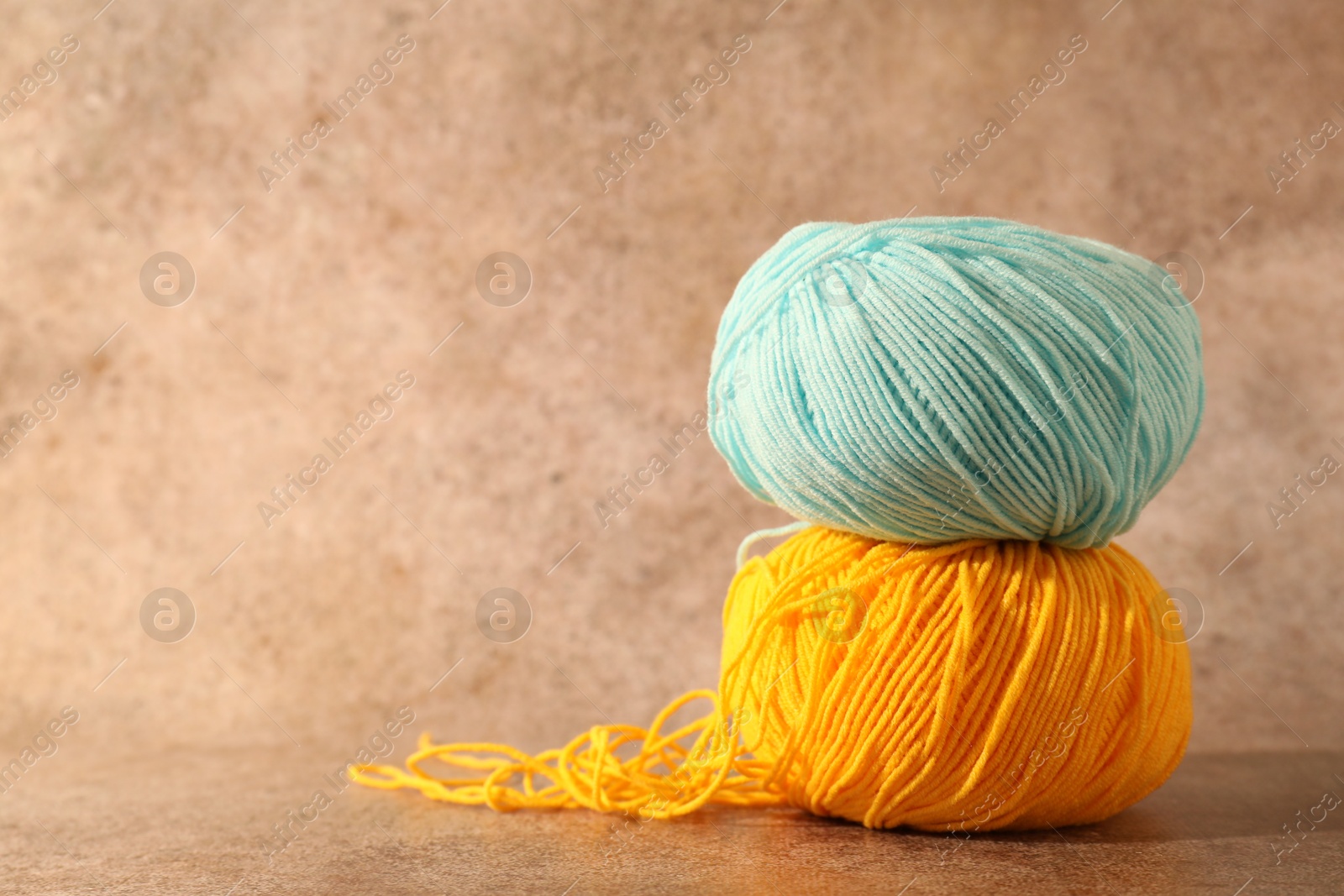 Photo of Two soft skeins of yarn on light brown background, space for text