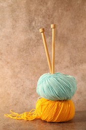 Photo of Two soft skeins of yarn and knitting needles on light brown background, space for text