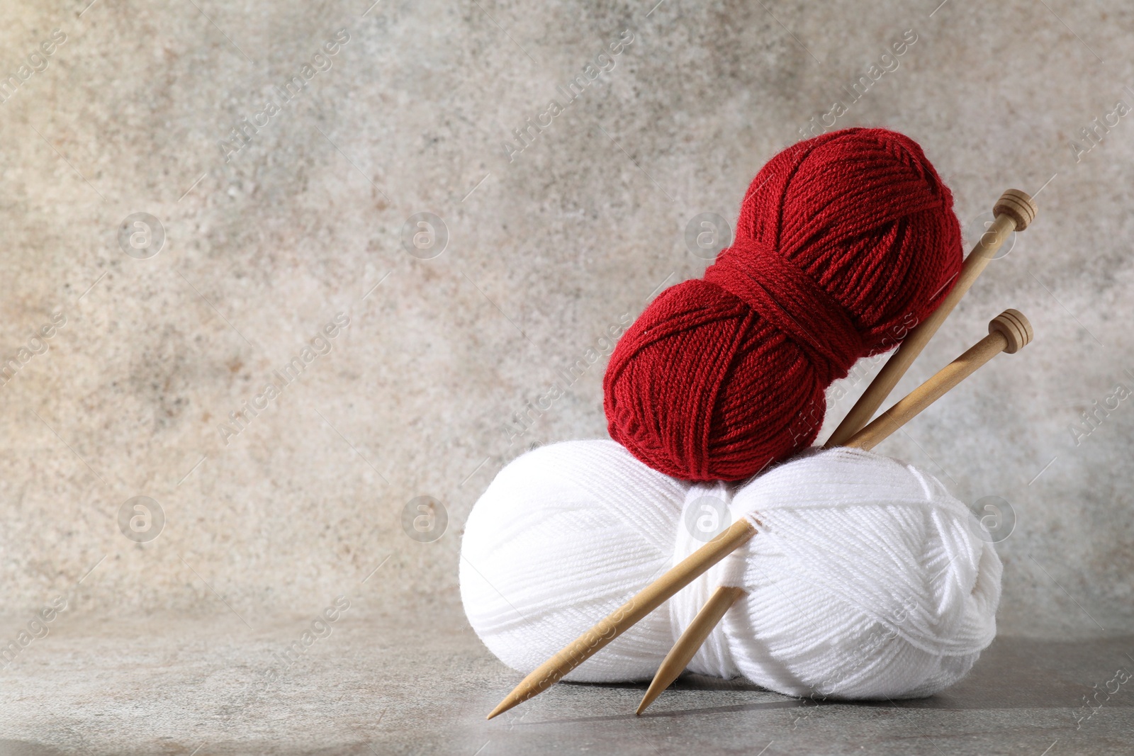 Photo of Two soft skeins of yarn and knitting needles on grey background, space for text