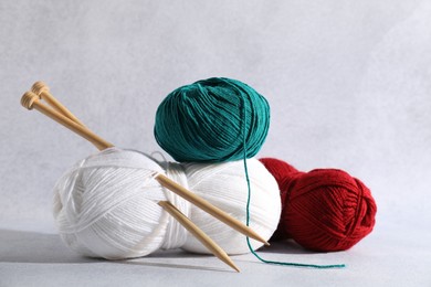 Photo of Soft skeins of yarn and knitting needles on light grey background