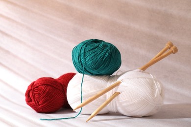 Photo of Soft skeins of yarn and knitting needles on beige background