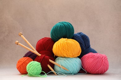 Photo of Many soft skeins of yarn and knitting needles on beige background