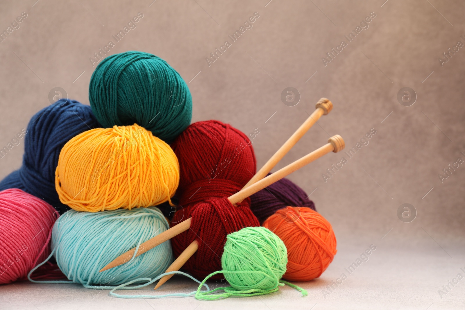 Photo of Many soft skeins of yarn and knitting needles on beige background, space for text