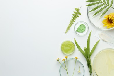 Photo of Petri dishes with green leaves, flowers and cosmetic products on white background, flat lay. Space for text