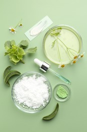 Petri dishes with leaves, chamomile flowers and cosmetic products on green background, flat lay