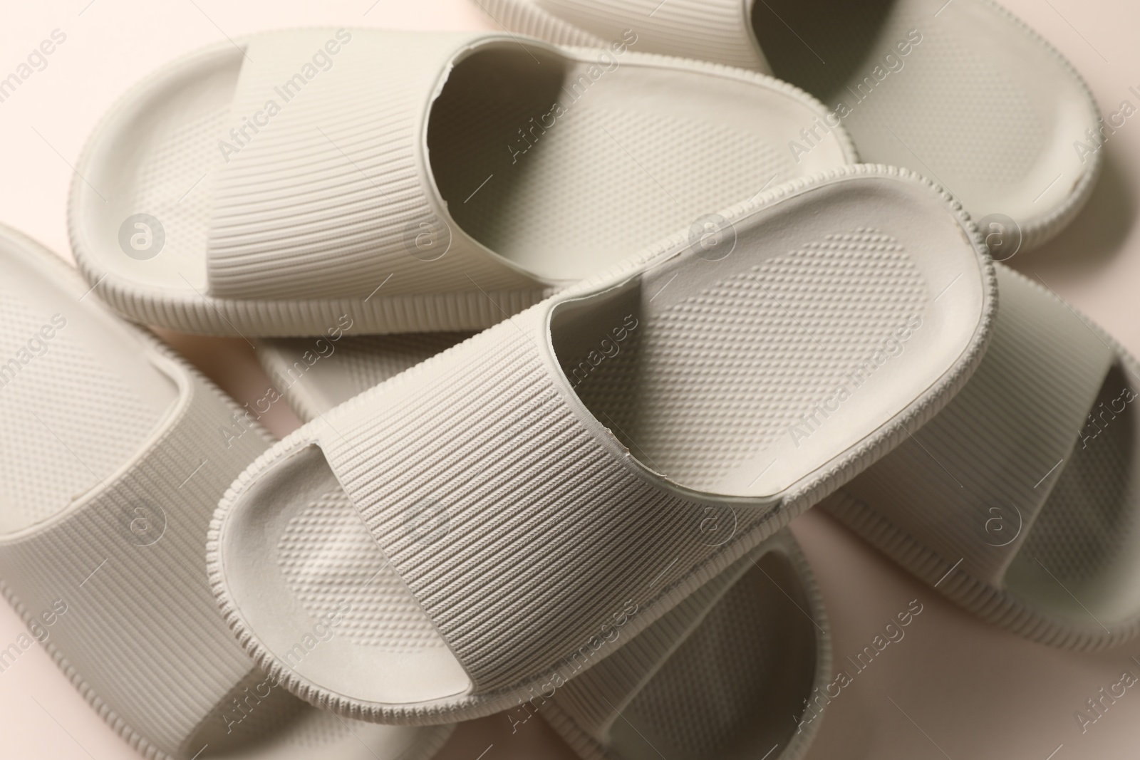 Photo of Pairs of rubber slippers on beige background, top view