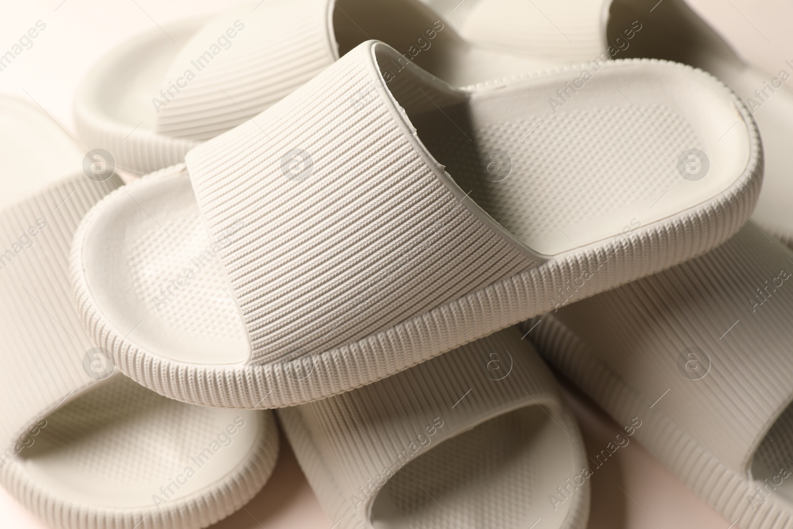 Photo of Pairs of rubber slippers on beige background, closeup