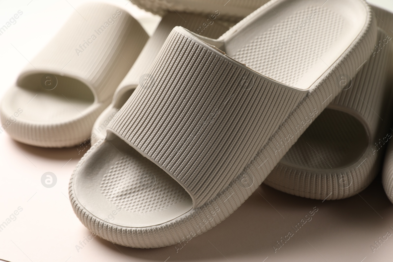 Photo of Pairs of rubber slippers on beige background, closeup