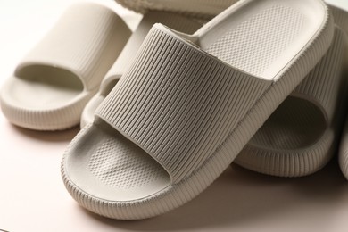 Photo of Pairs of rubber slippers on beige background, closeup