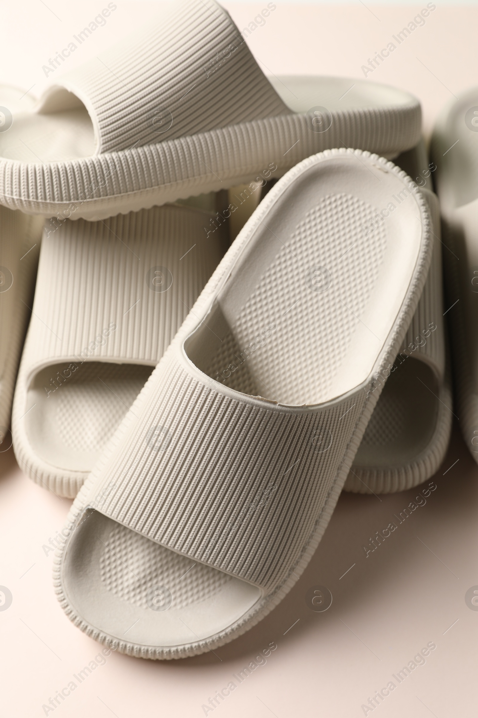 Photo of Pairs of rubber slippers on beige background, closeup