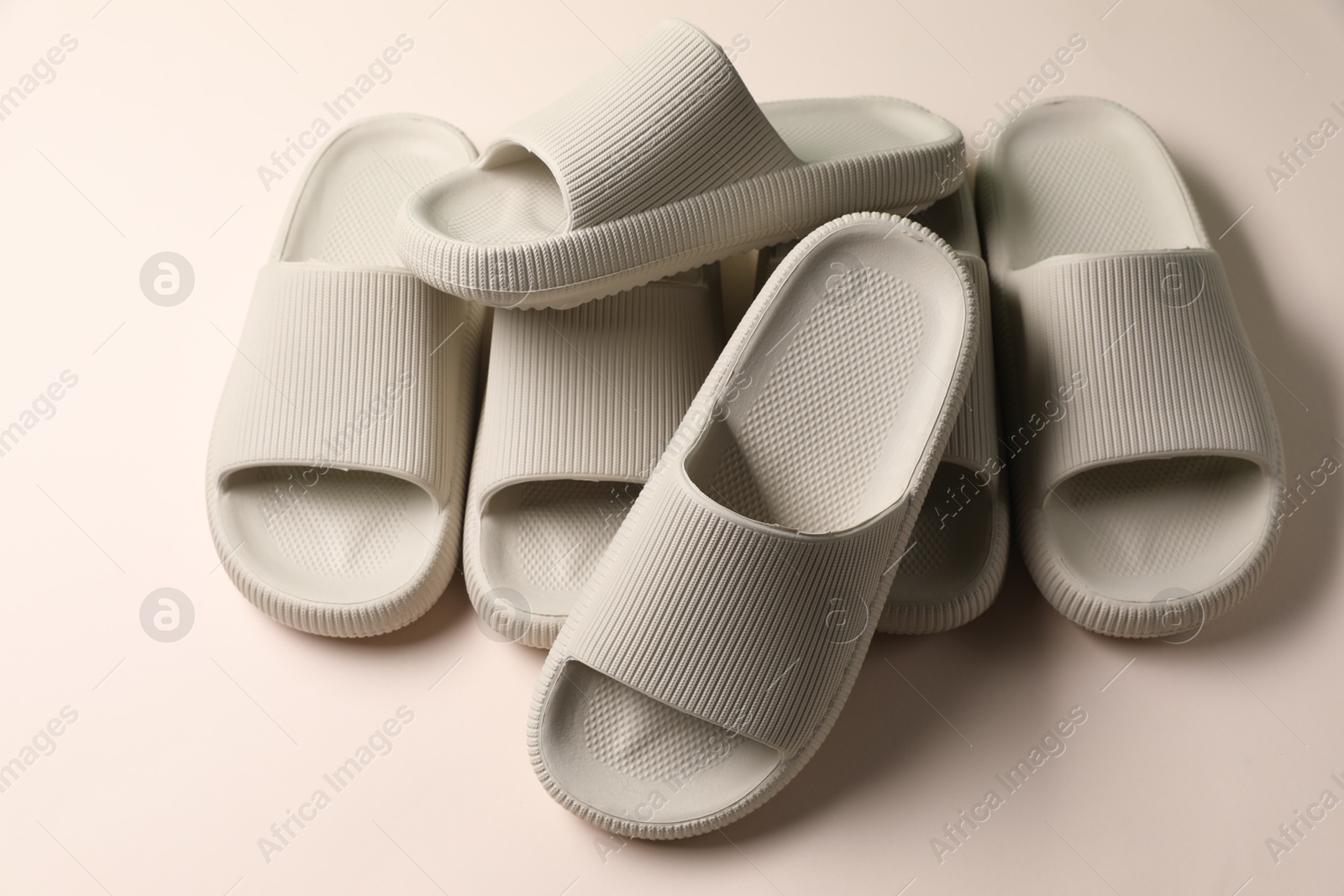 Photo of Pairs of rubber slippers on beige background