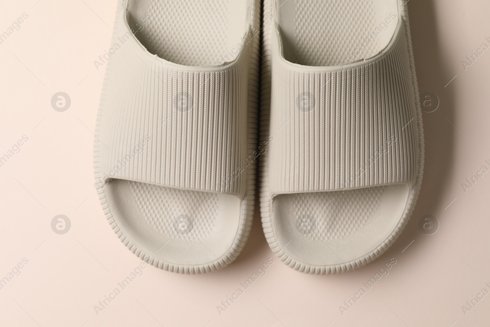 Photo of Pair of rubber slippers on beige background, top view