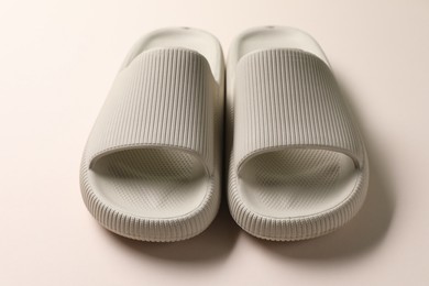 Photo of Pair of rubber slippers on beige background