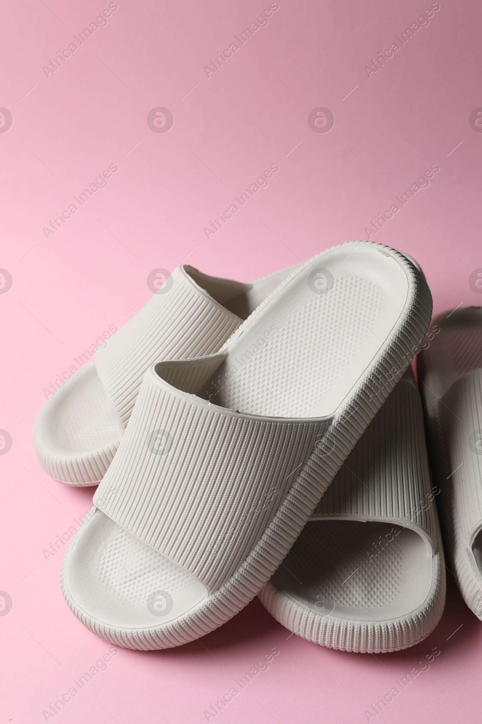 Photo of Pairs of rubber slippers on pink background, closeup