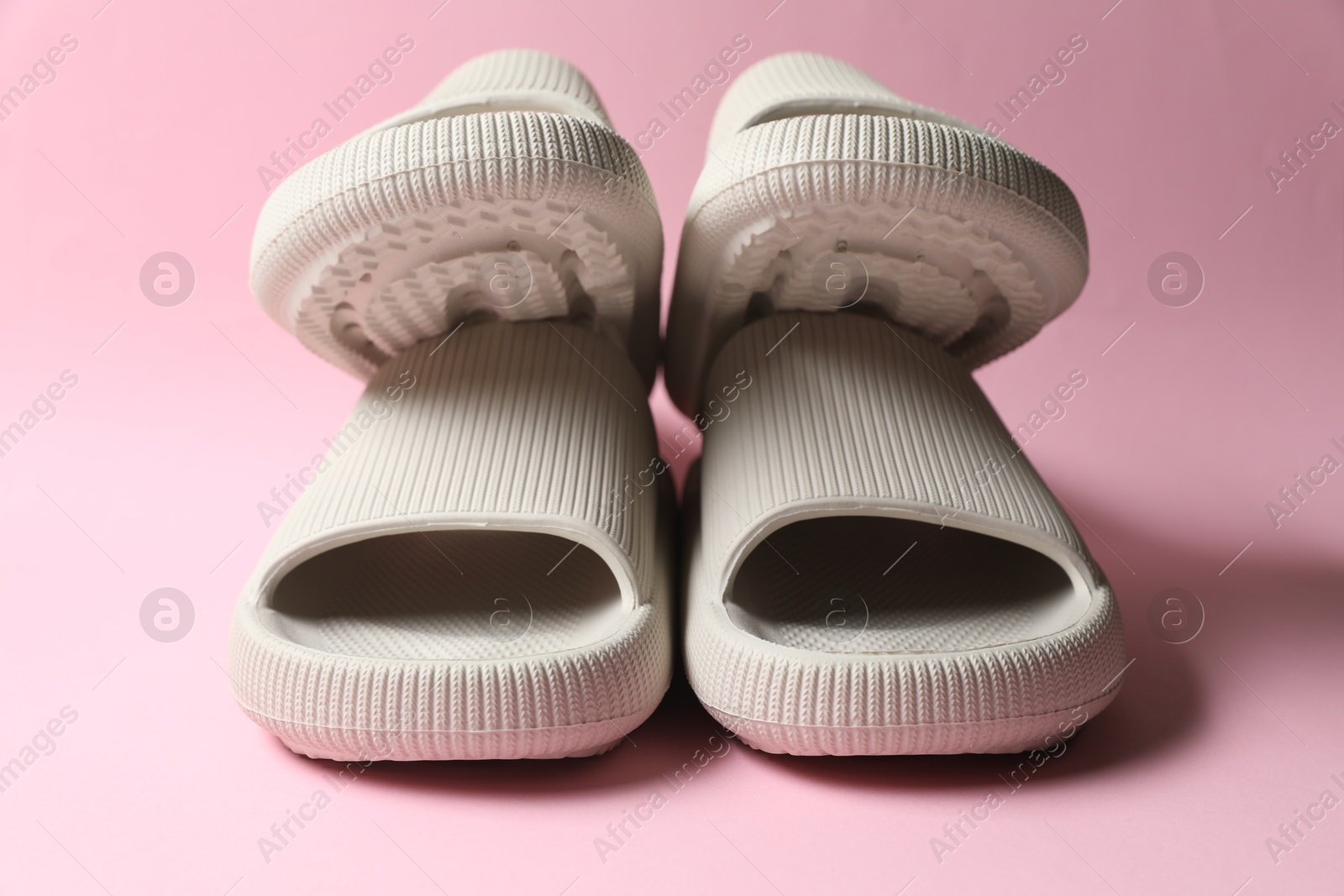 Photo of Pairs of rubber slippers on pink background, closeup