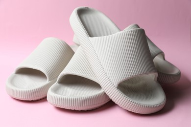 Photo of Pairs of rubber slippers on pink background, closeup