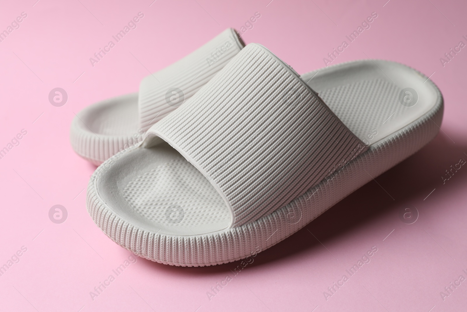 Photo of Pair of rubber slippers on pink background, closeup