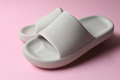 Photo of Pair of rubber slippers on pink background, closeup