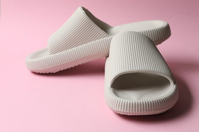 Photo of Pair of rubber slippers on pink background, closeup