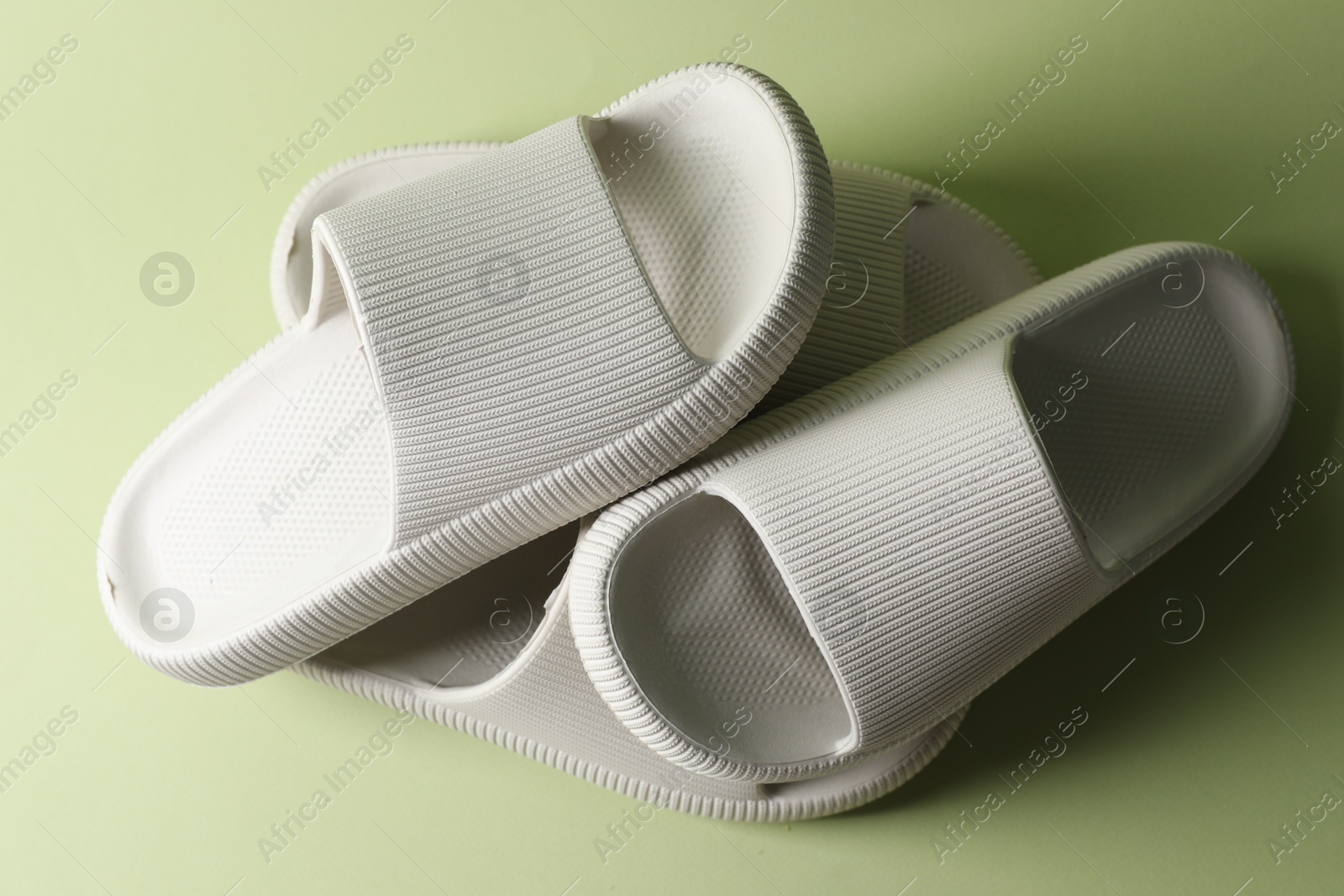 Photo of Pairs of slippers on green background, top view