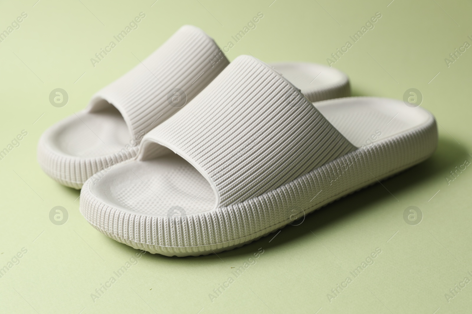 Photo of Pair of rubber slippers on green background