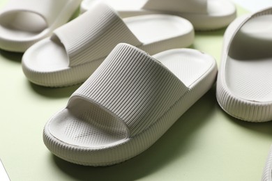 Photo of Pairs of slippers on green background, closeup