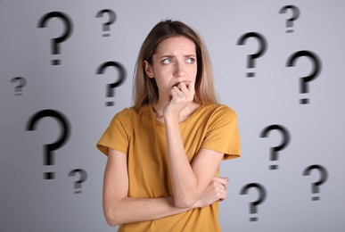 Image of Amnesia. Worried woman and question marks on grey background