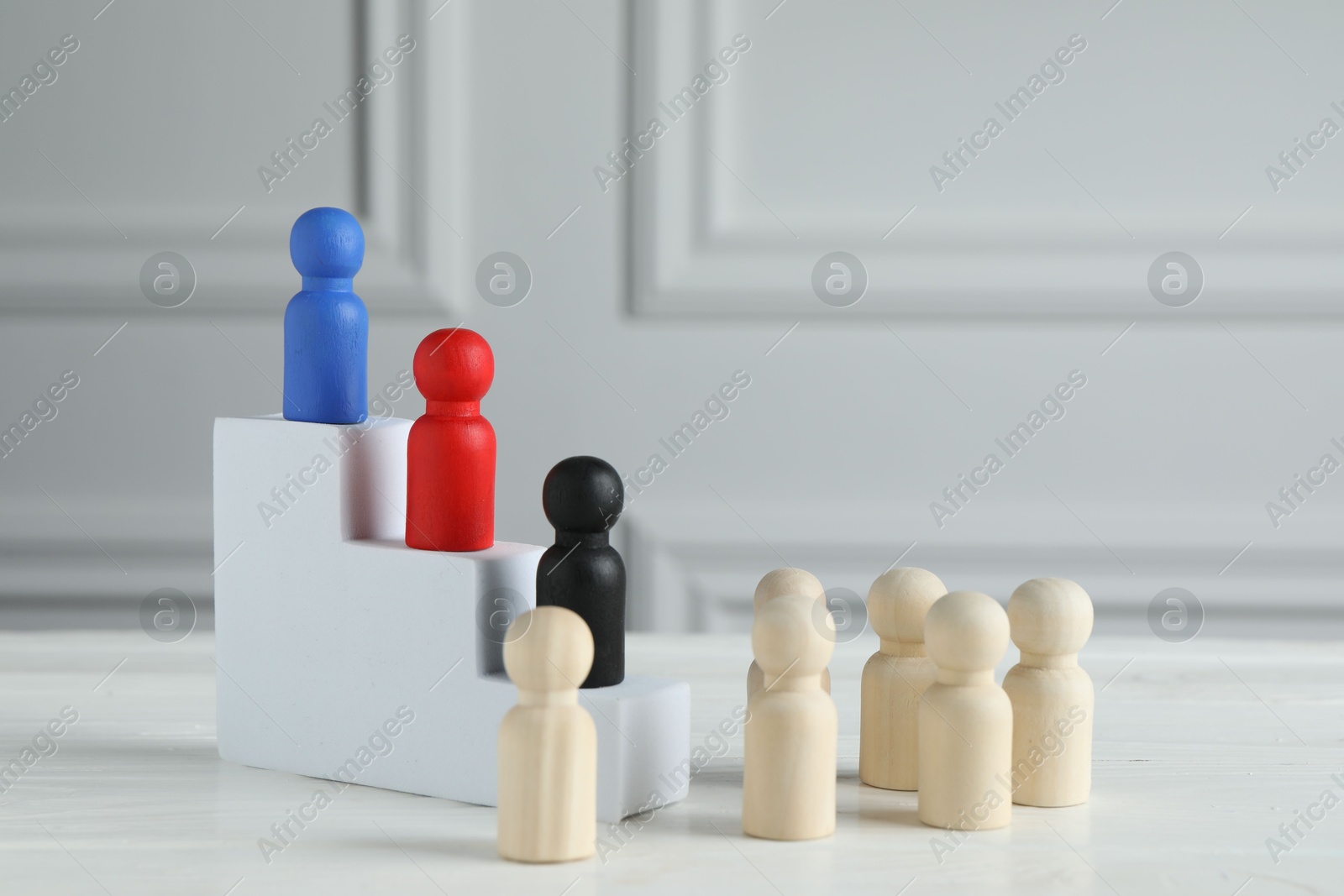 Photo of Stairs with group of different wooden human figures on white table