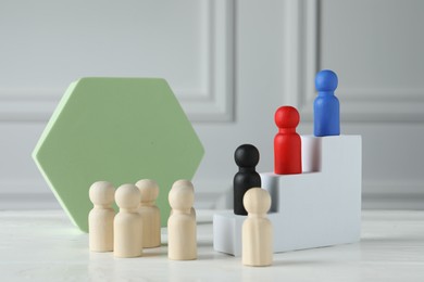 Photo of Stairs with group of different wooden human figures on white table