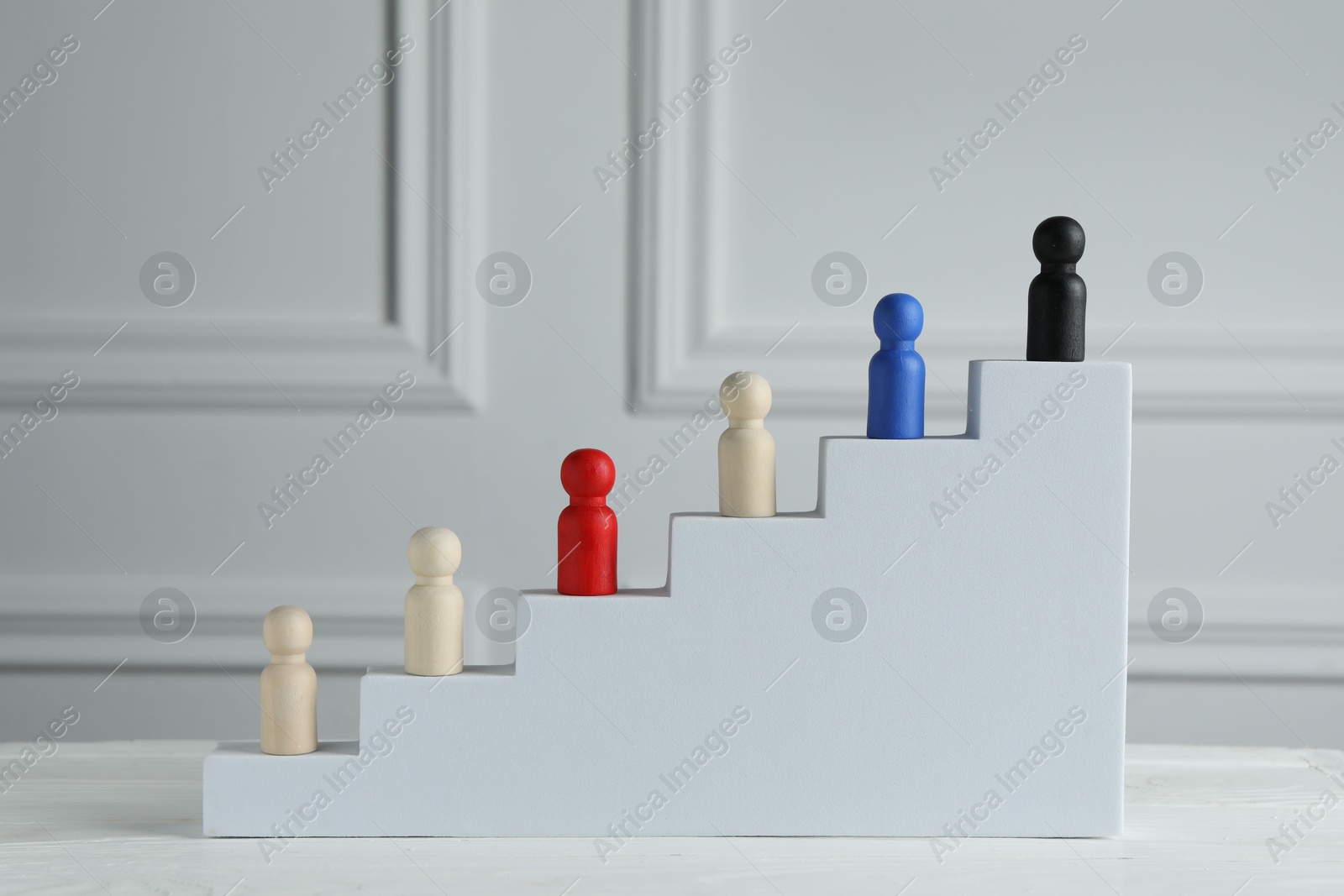 Photo of Stairs with group of different wooden human figures on white table