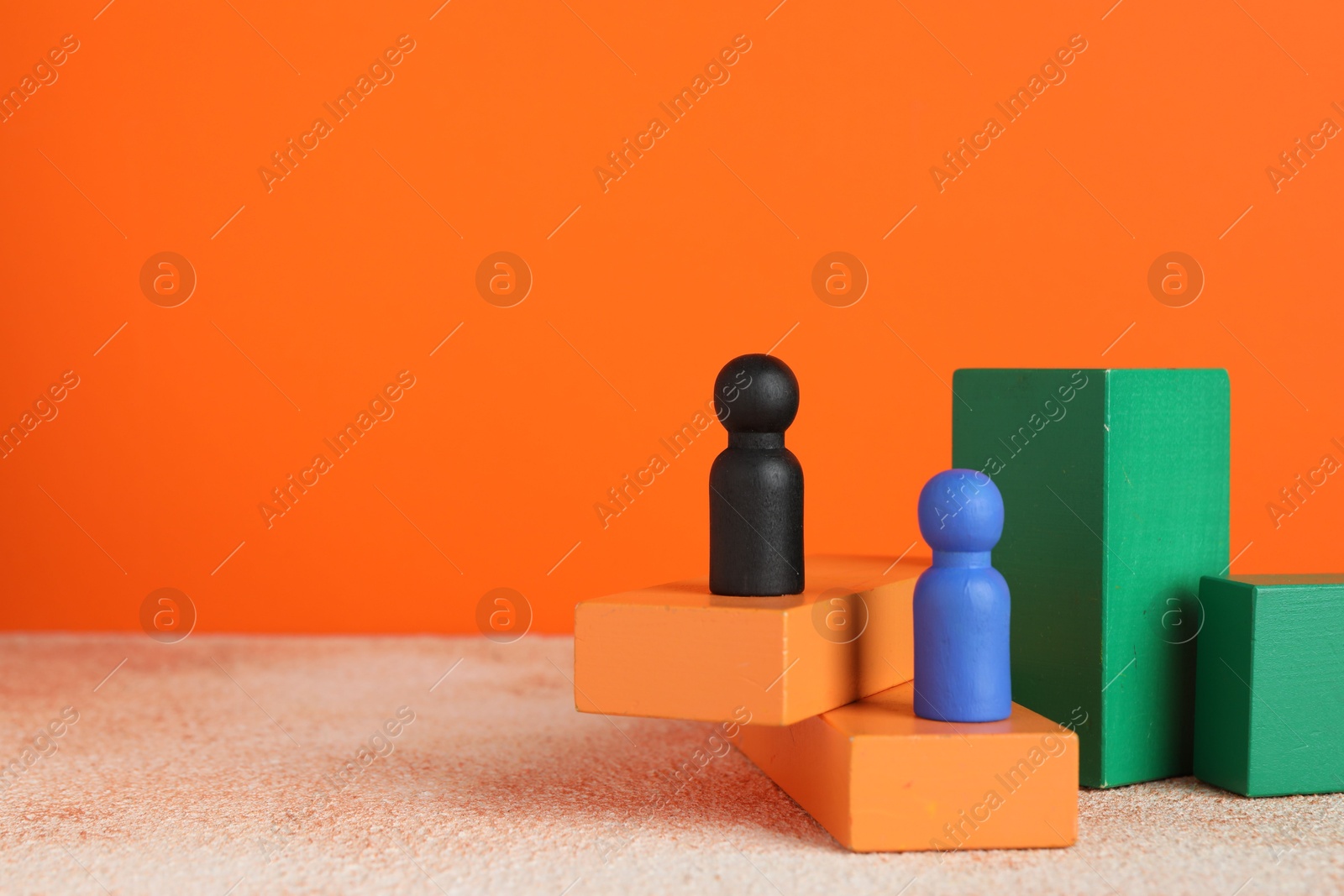 Photo of Different human figures on stands against orange background, space for text