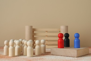 Photo of Different human figures on table against beige background