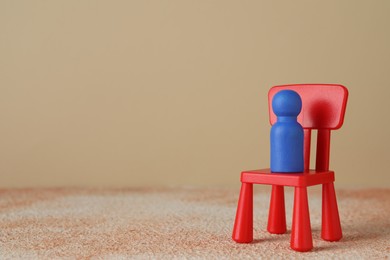 Photo of Blue human figure on chair against beige background, space for text