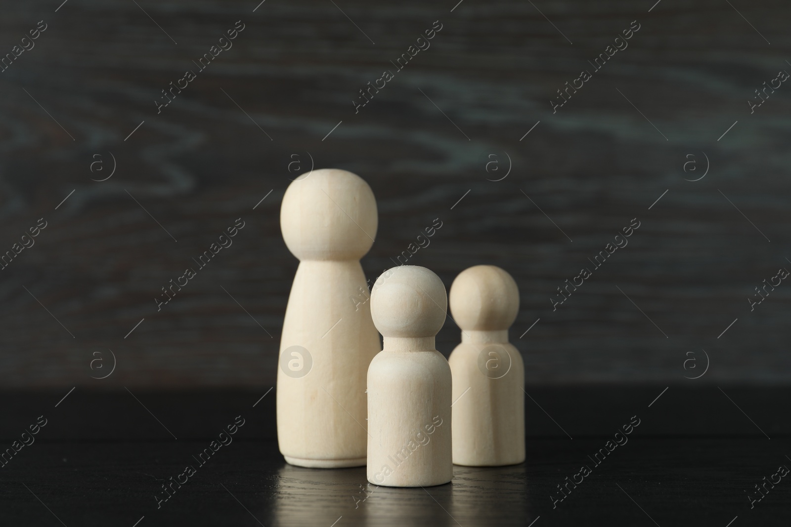 Photo of Group of wooden human figures on black table, closeup