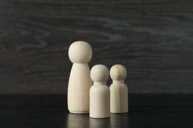 Group of wooden human figures on black table, closeup